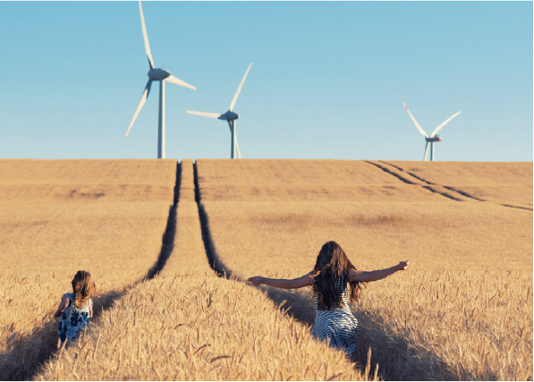 Our strategy for sustainable progress - children running through a wheat field with wind turbines